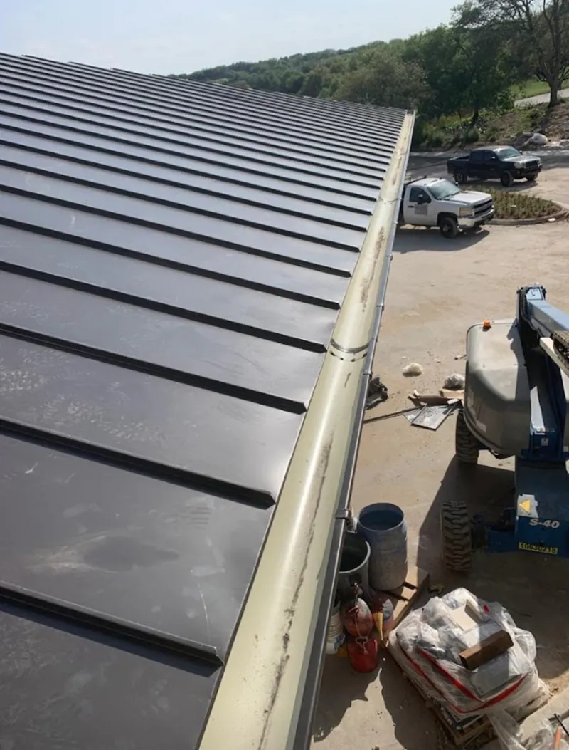 Standing seam panel and gutter detail on a metal roofing jobsite in Pinson